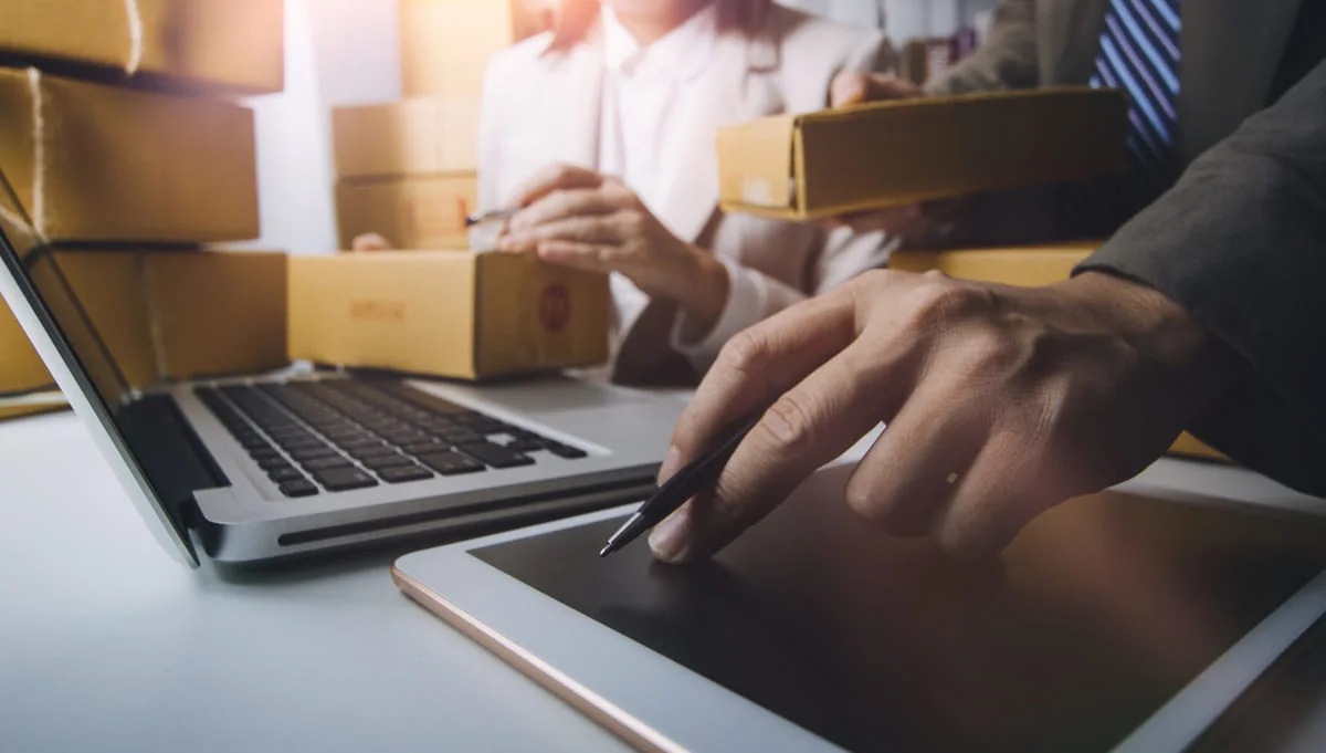 Echipă care procesează comenzi online cu laptop și tabletă pentru înregistrare fiscală eCommerce